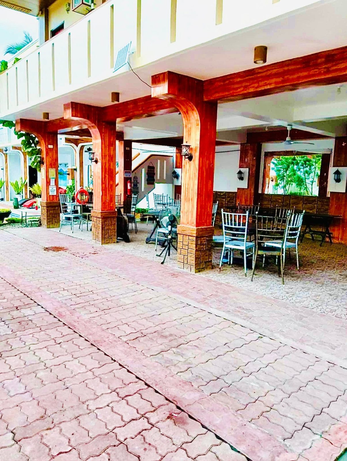 Covered arcade with wood-look columns, tables and chairs beside the courtyard